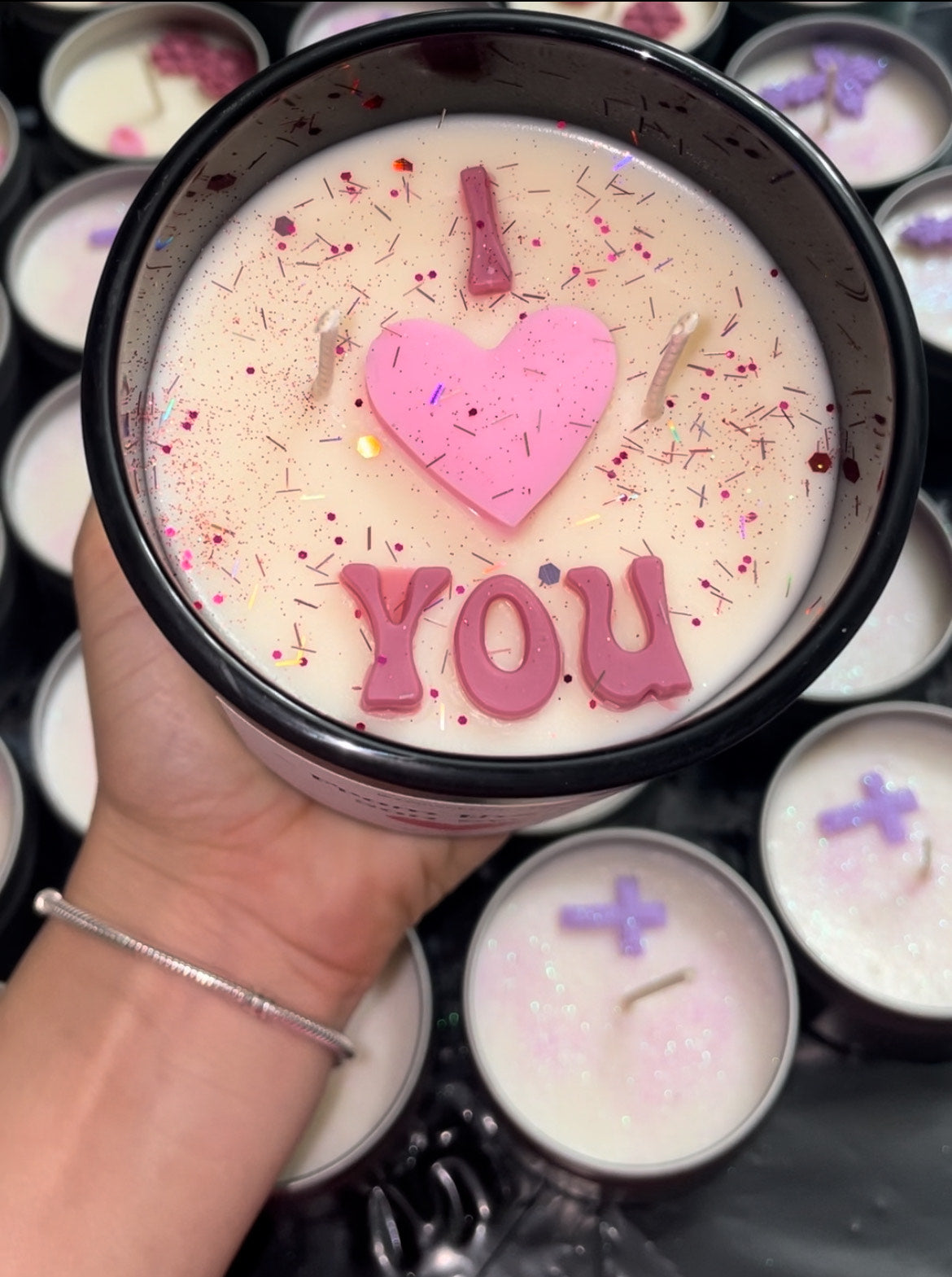 Candle with 'I love you' text held by a hand, surrounded by more candles.