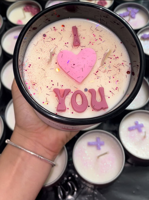 Candle with 'I love you' text held by a hand, surrounded by more candles.